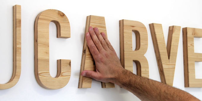 Exemple de fixation d'une enseigne intérieure (lettres et logo en bois) murale avec mousse double-face.